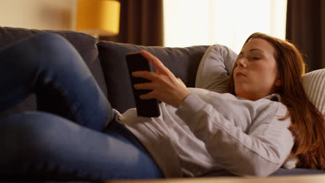 Close-Up-Of-Woman-Lying-On-Sofa-At-Home-At-Streaming-Or-Watching-Movie-Or-Show-Or-Scrolling-Internet-On-Mobile-Phone-2